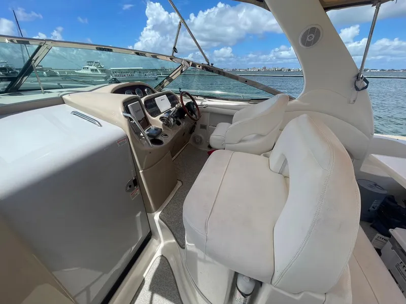 Slide: The Image of 2003 Sea Ray 360 Sundancer helm with white seating, overlooking marina and blue sky. - 10