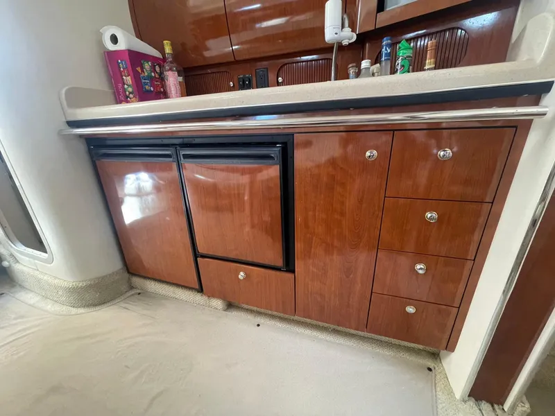 Slide: The Image of 2003 Sea Ray 360 Sundancer interior kitchen with wooden cabinets and countertop. - 26