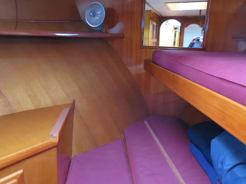 Slide: The Image of 1985 CHB Flush Deck Aft Cabin interior with wooden finish and purple bedding. - 13