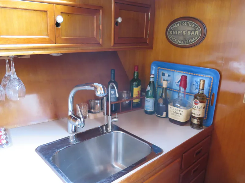 Slide: The Image of 1985 CHB Flush Deck Aftcabin kitchen with sink, liquor bottles, and wooden cabinets. - 15