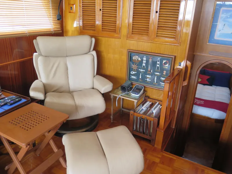 Slide: The Image of Interior of 1985 CHB Flush Deck Aft Cabin with beige chair, wooden decor, and nautical artwork. - 21
