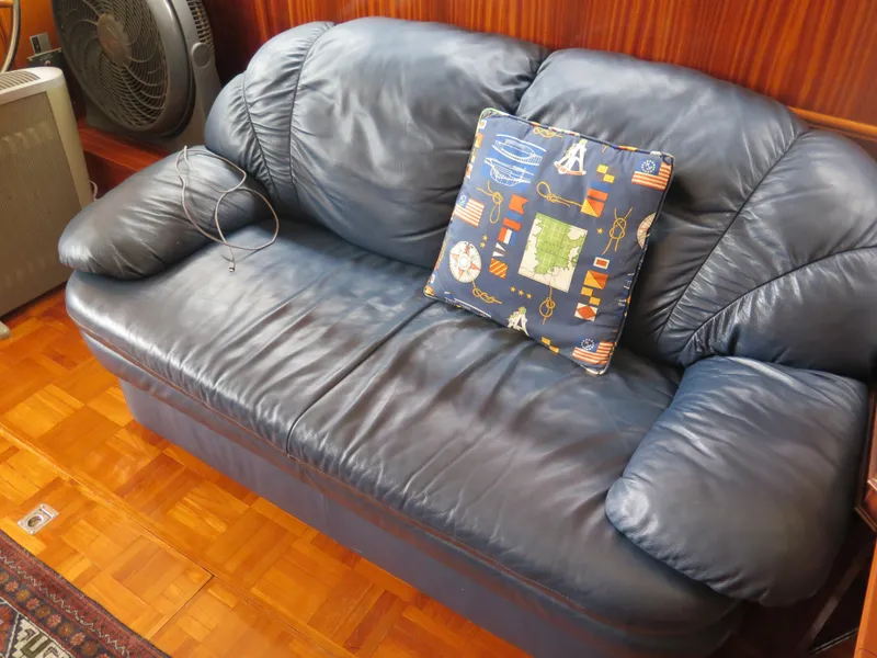 Slide: The Image of Blue leather sofa with nautical-themed cushion on a wooden floor in a 1985 CHB Flush Deck Aftcabin. - 22