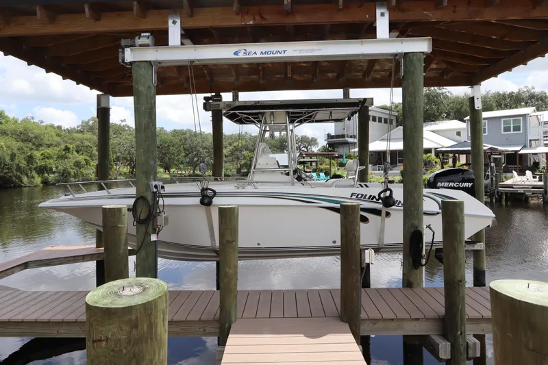 The Image of 2001 Fountain 25CC boat on lift, docked by waterfront homes. - 0