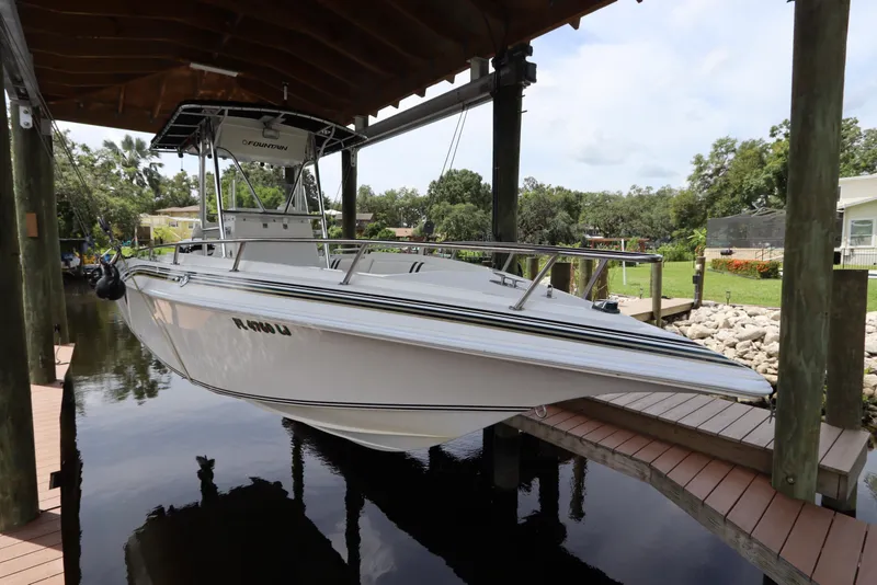 Slide: The Image of 2001 Fountain 25CC boat docked under a wooden canopy, surrounded by lush greenery. - 1