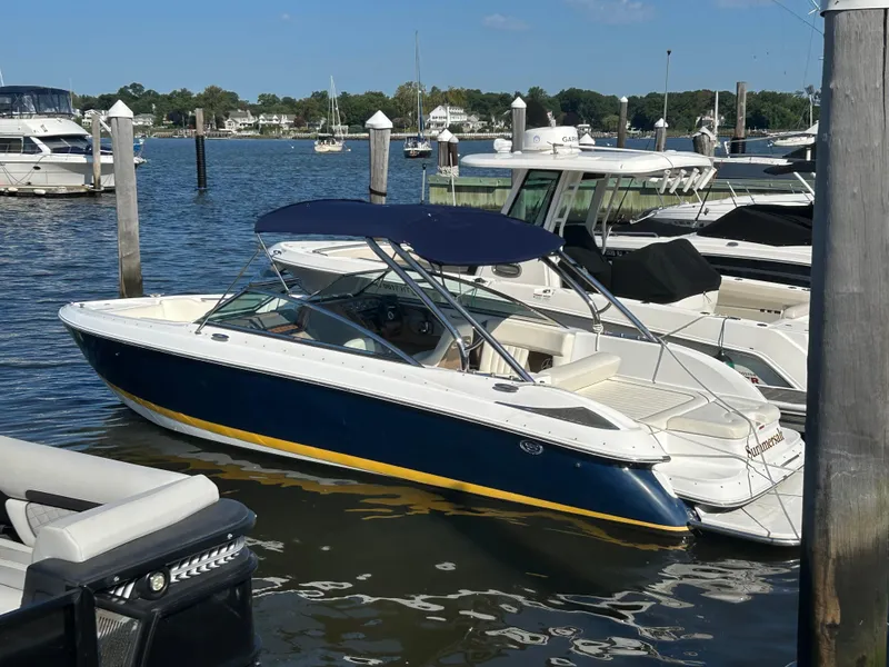 Slide: The Image of 2008 Cobalt 272 boat docked in a marina, featuring a blue and white design with a canopy. - 2