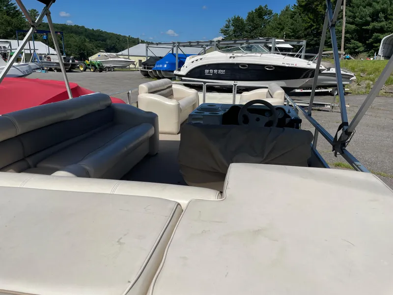 Slide: The Image of 1999 Harris Sunliner 240 pontoon boat with beige seating, parked outdoors near other boats. - 10