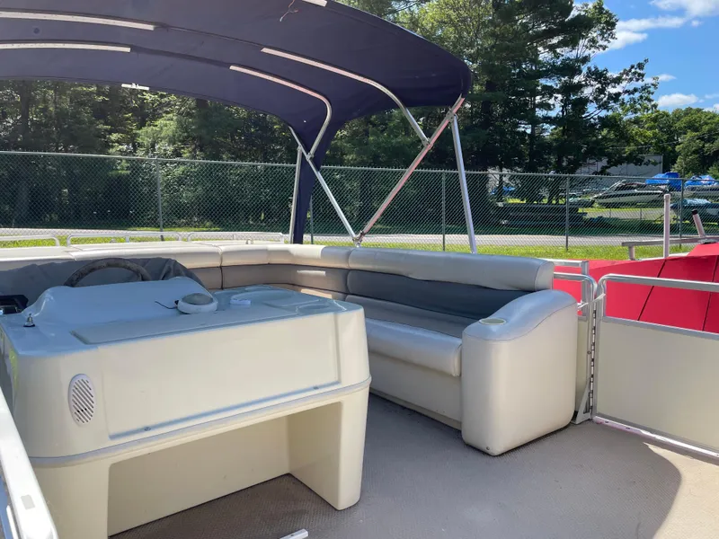 Slide: The Image of 1999 Harris Sunliner 240 pontoon boat interior with seating and canopy, parked outdoors. - 3