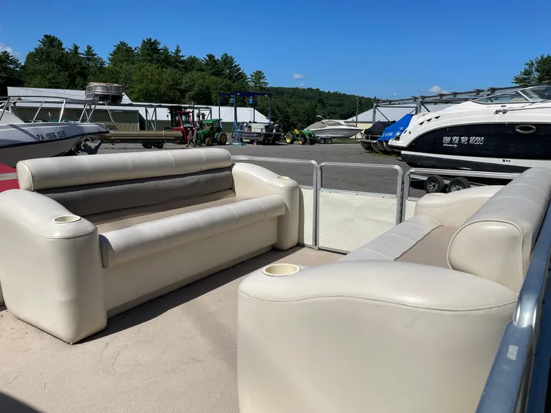 Slide: The Image of 1999 Harris Sunliner 240 pontoon boat with beige seating, docked near other boats. - 4