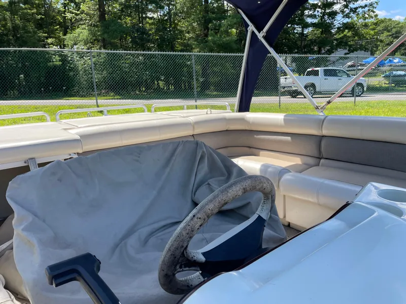 Slide: The Image of 1999 Harris Sunliner 240 boat interior with covered steering wheel and cushioned seating. - 5