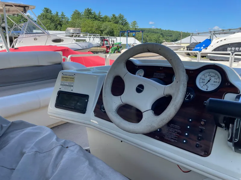 Slide: The Image of 1999 Harris Sunliner 240 boat dashboard with steering wheel and gauges, docked outdoors. - 6