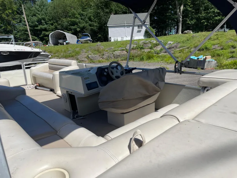 Slide: The Image of 1999 Harris Sunliner 240 pontoon boat interior with beige seating and covered steering console. - 8