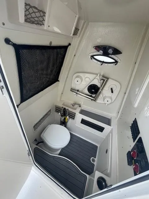 Slide: The Image of 2023 Sailfish 272 CC boat interior with compact bathroom, featuring a toilet and storage. - 12
