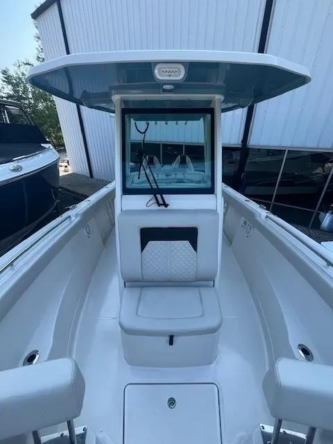 Slide: The Image of 2023 Sailfish 272 CC boat interior with seating and console, docked near a building. - 8