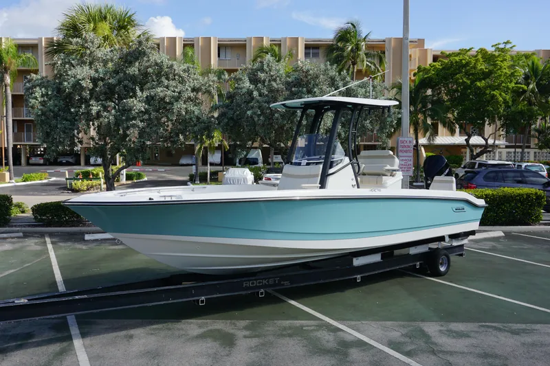 The Image of 2026 Boston Whaler 250 Dauntless boat on trailer in parking lot, surrounded by trees. - 0