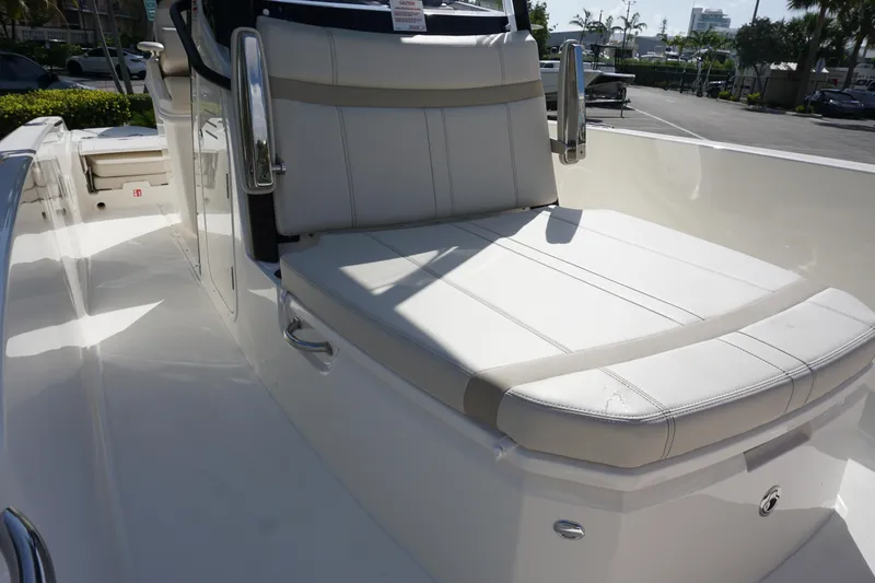 Slide: The Image of 2026 Boston Whaler 250 Dauntless boat with white cushioned seating in a sunny marina. - 21
