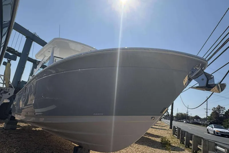 Slide: The Image of 2026 Blackfin 272 DC boat under bright sunlight, docked near a road. - 3