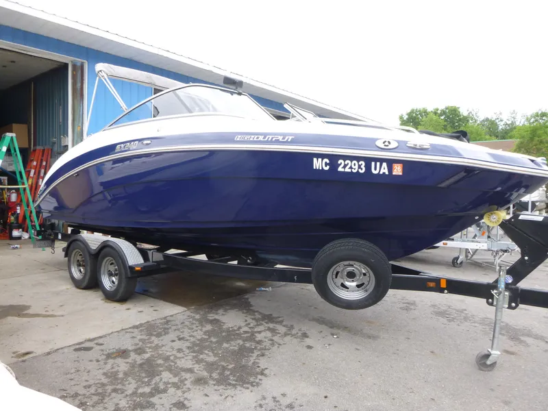 Slide: The Image of 2013 Yamaha Boats SX240 HO on trailer, blue hull, parked outside a garage. - 1