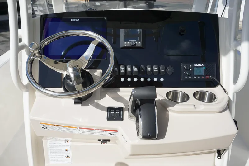 Slide: The Image of 2026 Boston Whaler 220 Dauntless helm with steering wheel, controls, and Simrad electronics. - 17