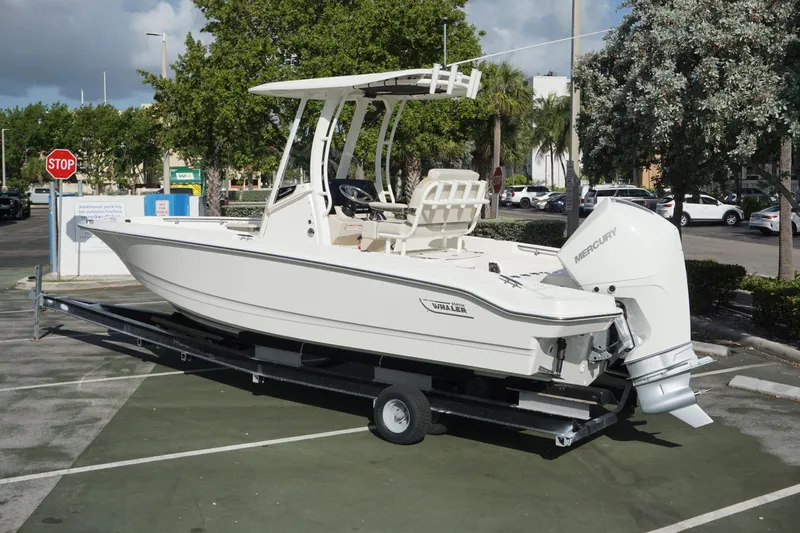 Slide: The Image of 2026 Boston Whaler 220 Dauntless boat on trailer in parking lot. - 2