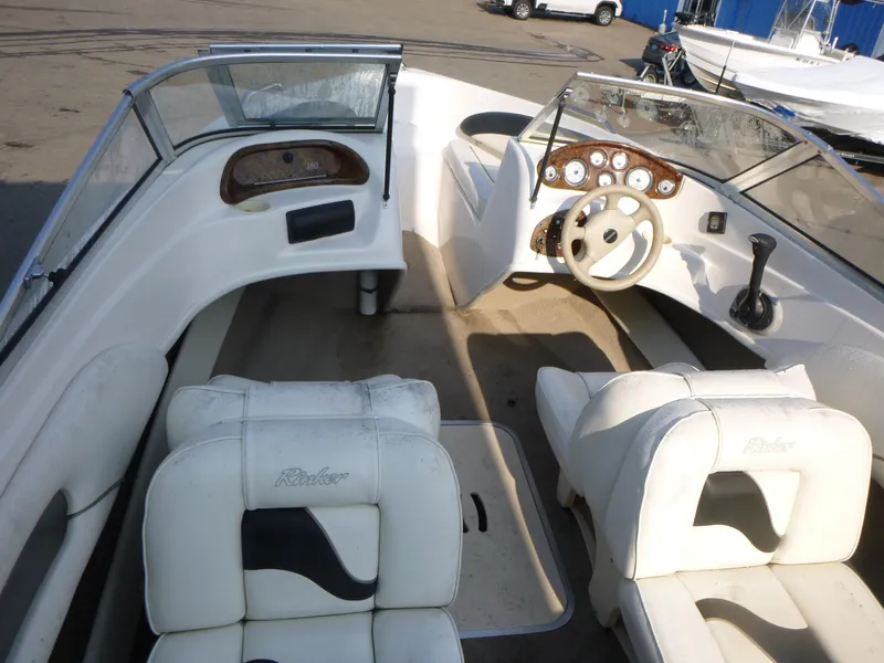 Slide: The Image of 2003 Rinker 180 BR boat interior with white seating and dashboard controls. - 5