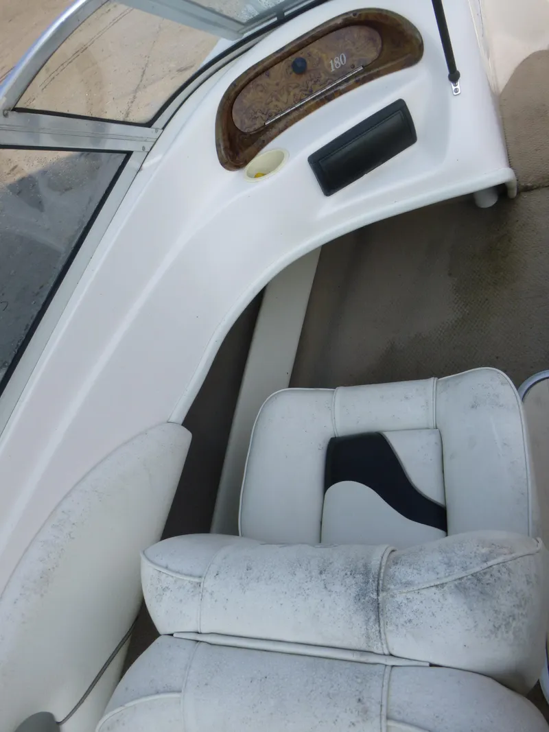 Slide: The Image of 2003 Rinker 180 BR boat interior with white seating and dashboard details. - 9