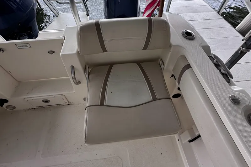 Slide: The Image of 2013 World Cat 255 DC boat seat with beige upholstery and armrest, dockside view. - 14