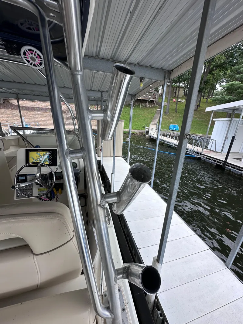 Slide: The Image of 2013 World Cat 255 DC boat interior with rod holders, docked by a lakeside pier. - 17