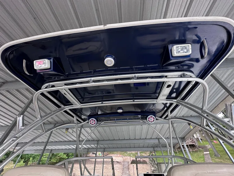 Slide: The Image of 2013 World Cat 255 DC boat canopy with integrated lights and speakers under a metal roof. - 18