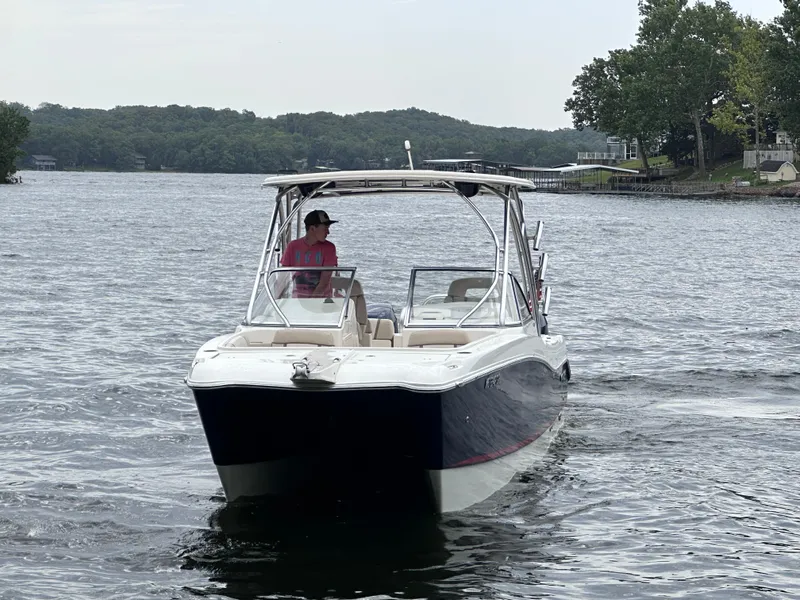 Slide: The Image of 2013 World Cat 255 DC boat cruising on a scenic lake with lush green shoreline. - 21