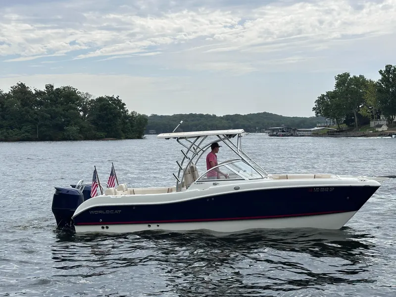 Slide: The Image of 2013 World Cat 255 DC boat cruising on a lake with American flags. - 23