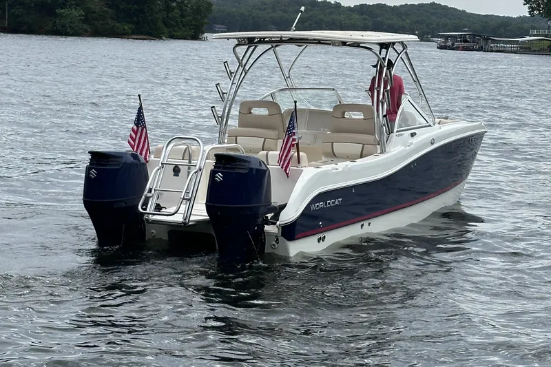 Slide: The Image of 2013 World Cat 255 DC boat on water, dual engines, American flags, scenic lake background. - 26