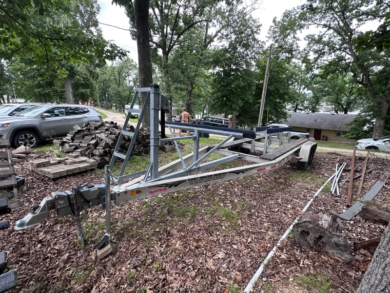 Slide: The Image of Trailer for 2013 World Cat 255 DC boat, parked outdoors among trees and vehicles. - 30