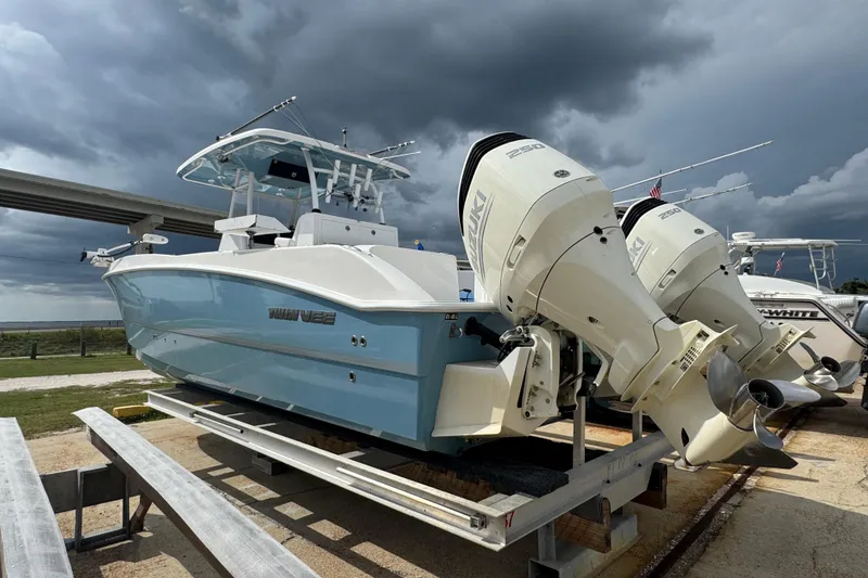 Slide: The Image of 2021 Twin Vee 280 CC GF boat with dual Suzuki engines on a trailer under stormy skies. - 35