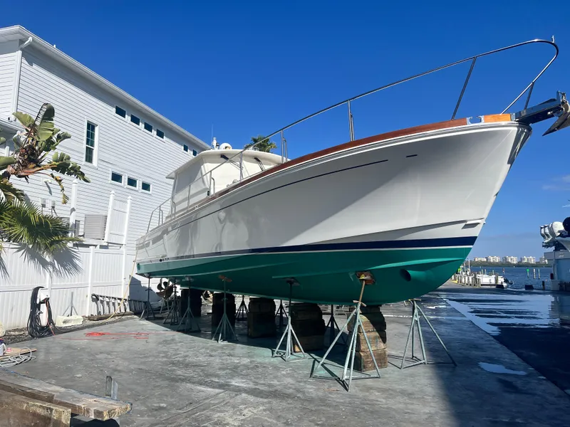 Slide: The Image of 2002 Grand Banks 43 Eastbay HX yacht on stands, dockside with blue sky background. - 12
