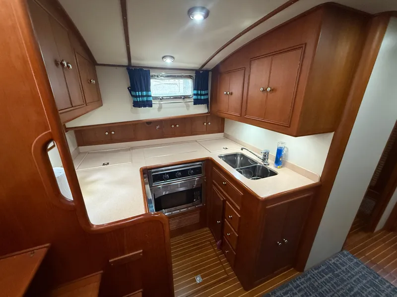 Slide: The Image of Luxurious 2002 Grand Banks 43 Eastbay HX yacht kitchen with wood cabinetry and modern appliances. - 34
