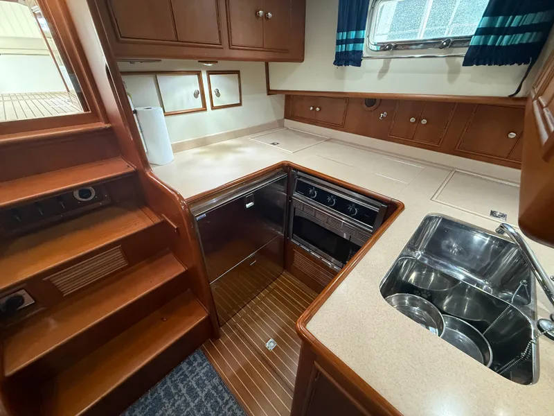Slide: The Image of Luxurious 2002 Grand Banks 43 Eastbay HX yacht kitchen with wood cabinetry and modern appliances. - 35