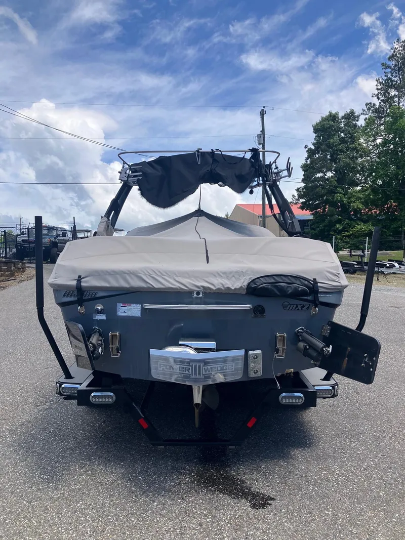 Slide: The Image of 2019 Malibu Wakesetter 22 MXZ boat, rear view, parked on pavement under a cloudy sky. - 2