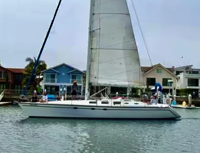 Slide: The Image of 1987 Hunter Legend 45 sailboat on calm water near waterfront homes. - 0