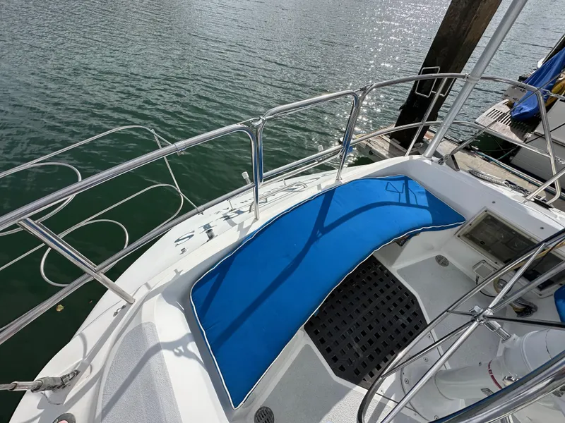 Slide: The Image of 1987 Hunter Legend 45 sailboat deck with blue seating, docked by calm waters. - 19