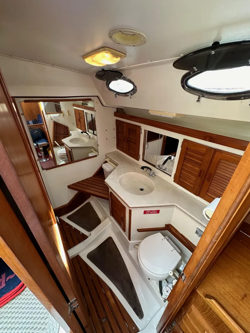 Slide: The Image of Interior of 1987 Hunter Legend 45 yacht bathroom with wooden accents and porthole windows. - 38