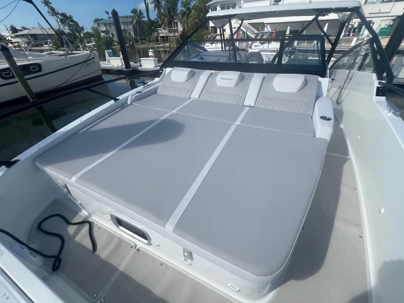 Slide: The Image of 2025 Beneteau Flyer 10 boat with spacious sunbed and sleek design in marina setting. - 10