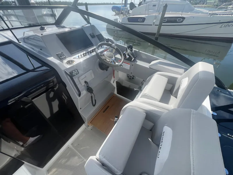 Slide: The Image of 2025 Beneteau Flyer 10 cockpit with modern controls and comfortable seating, docked by the water. - 14