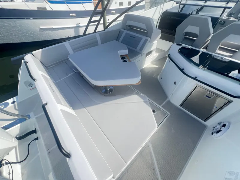 Slide: The Image of 2025 Beneteau Flyer 10 boat interior with seating and table, docked at marina. - 18