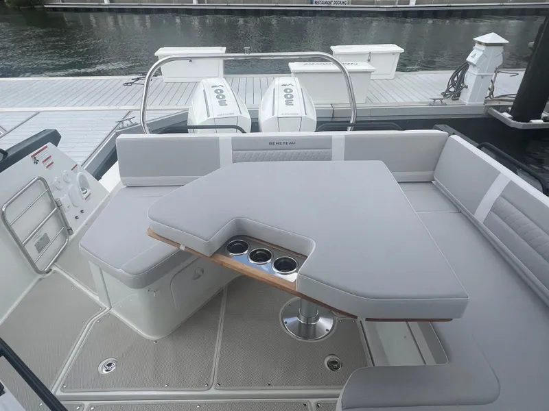Slide: The Image of 2025 Beneteau Flyer 10 boat interior with cushioned seating and table, docked by the water. - 19