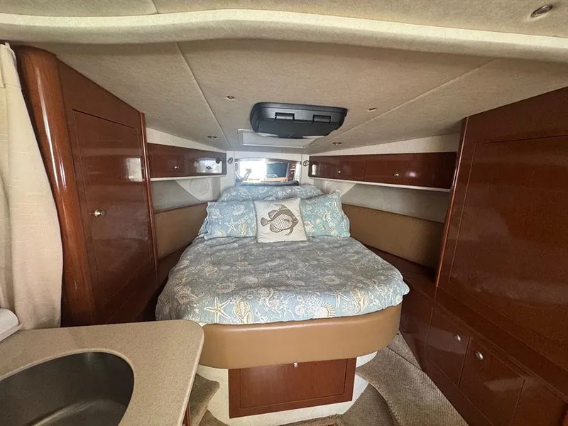 Slide: The Image of 2009 Sea Ray 330 Sundancer cabin interior with bed and wood cabinetry. - 13