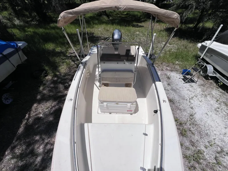 Slide: The Image of 2000 Scout 185 Sportfish boat with canopy, parked on grass. - 21