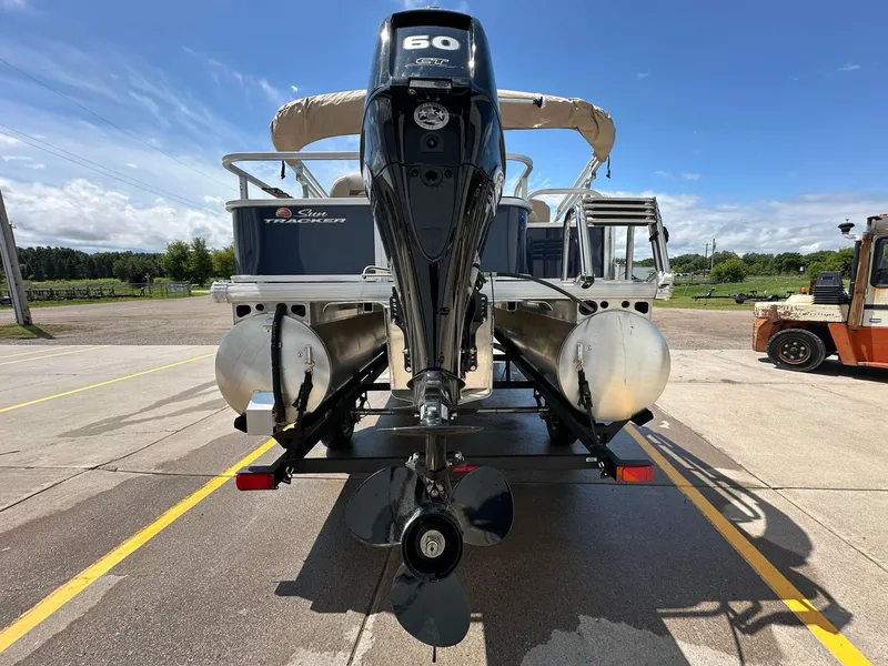 Slide: The Image of 2025 Sun Tracker Bass Buggy 18 DLX pontoon boat with outboard motor, parked outdoors. - 30