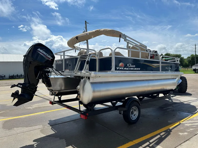 Slide: The Image of 2025 Sun Tracker Bass Buggy 18 DLX pontoon boat on trailer, with Mercury outboard motor. - 4