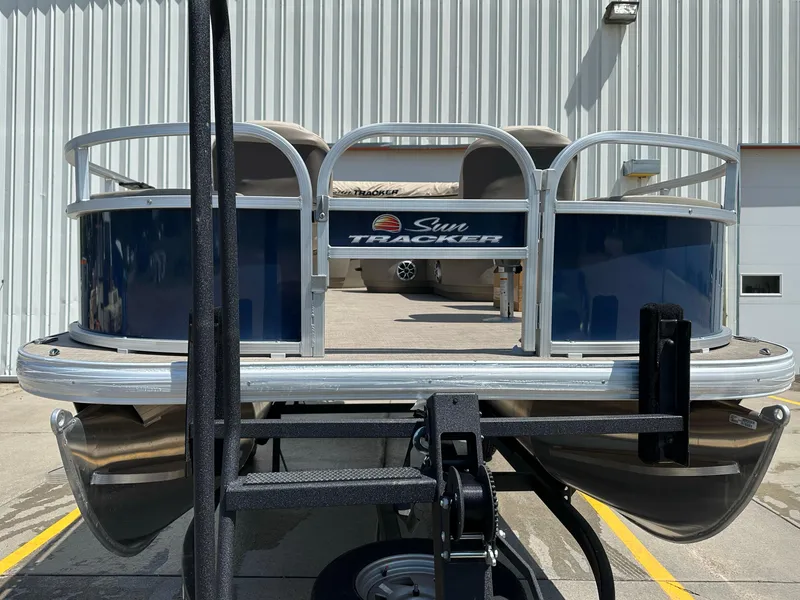 Slide: The Image of 2025 Sun Tracker Bass Buggy 18 DLX pontoon boat, front view, parked outdoors. - 7