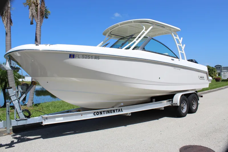 Slide: The Image of 2018 Boston Whaler 270 Vantage boat on trailer, parked near palm trees. - 1